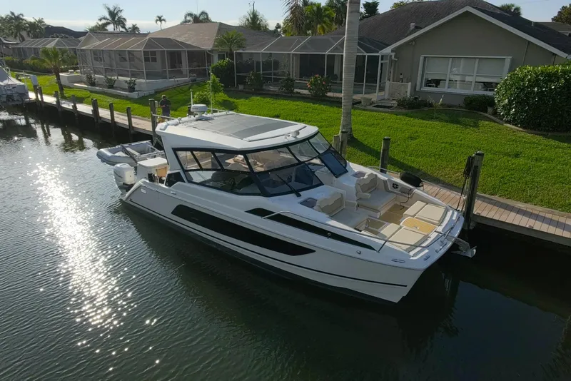Slide: The Image of Aquila 36 Sport 2019 yacht docked by waterfront homes, reflecting sunlight on water. - 6