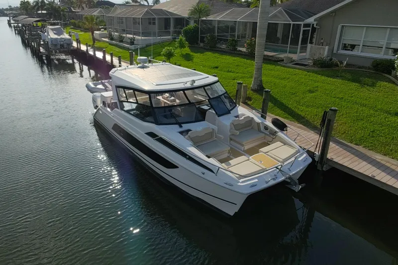 Slide: The Image of Aquila 36 Sport 2019 yacht docked by waterfront homes, showcasing sleek design and spacious deck. - 7
