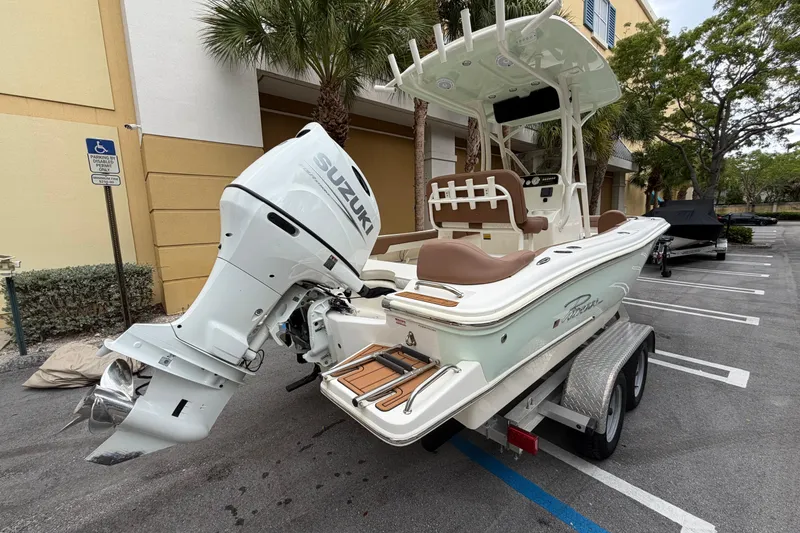 Slide: The Image of 2023 Pioneer 202 Islander boat with Suzuki outboard motor on a trailer in a parking lot. - 2
