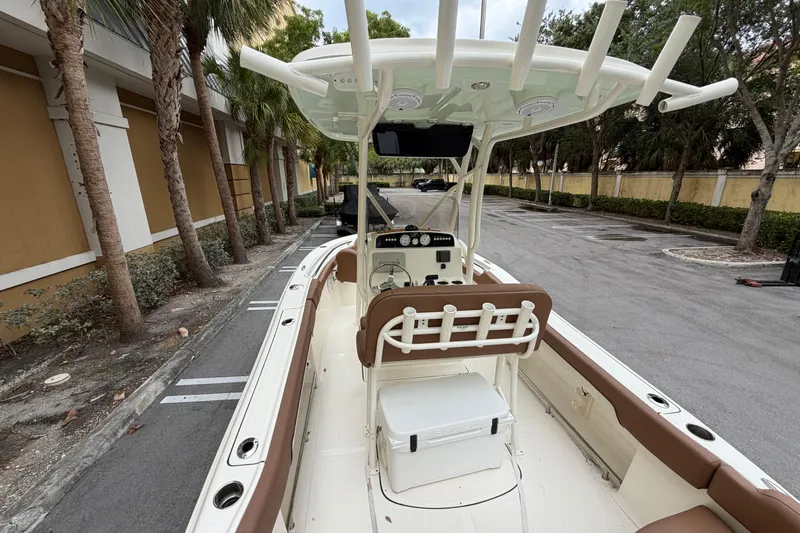 Slide: The Image of 2023 Pioneer 202 Islander boat with seating and console, parked near palm trees. - 5