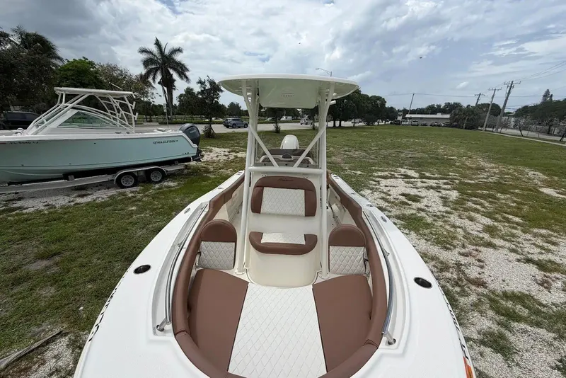 Slide: The Image of 2023 Pioneer 202 Islander boat with brown and white seating, parked on grassy area. - 9