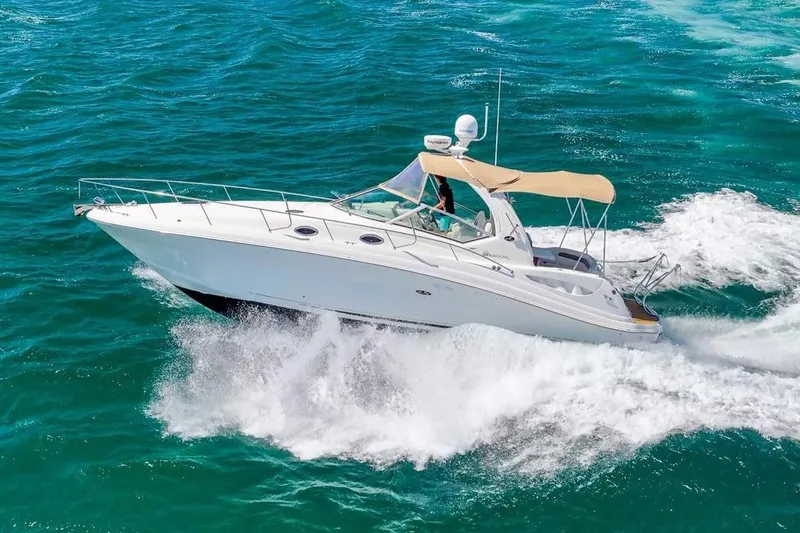 The Image of A white motorboat speeds across blue water, featuring a beige sunshade. - 0