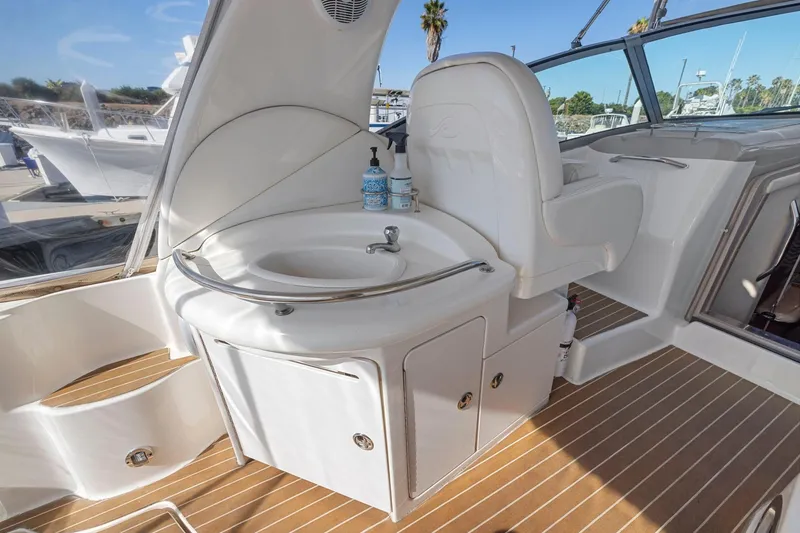 Slide: The Image of 2004 Sea Ray 340 Sundancer cockpit with sink and seating, featuring teak flooring. - 12