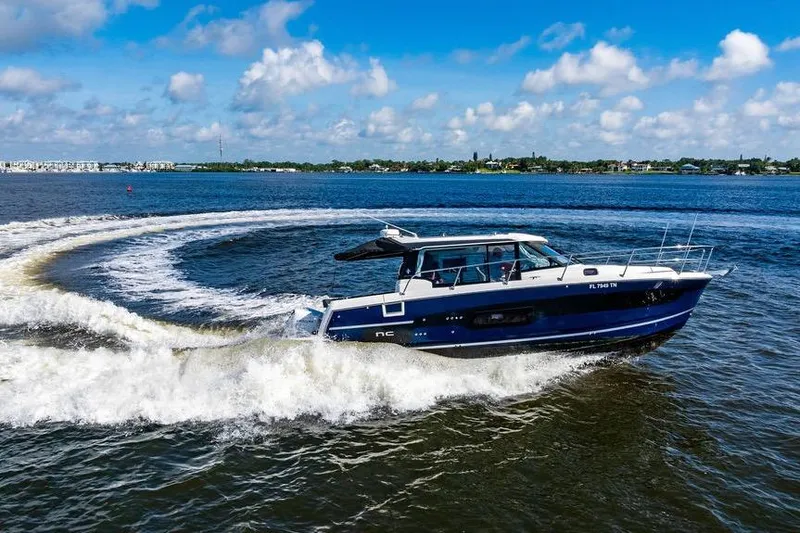 Slide: The Image of 2023 Jeanneau NC 1095 cruising on a sunny day, creating a circular wake. - 13