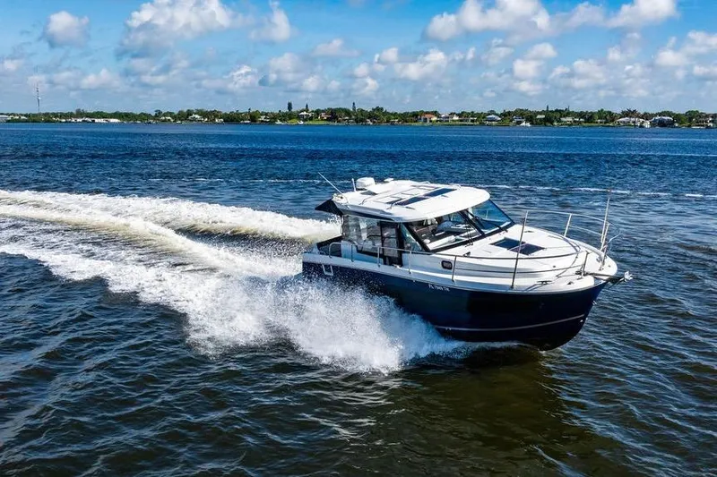 Slide: The Image of 2023 Jeanneau NC 1095 cruising on a sunny day, creating waves in the blue water. - 14