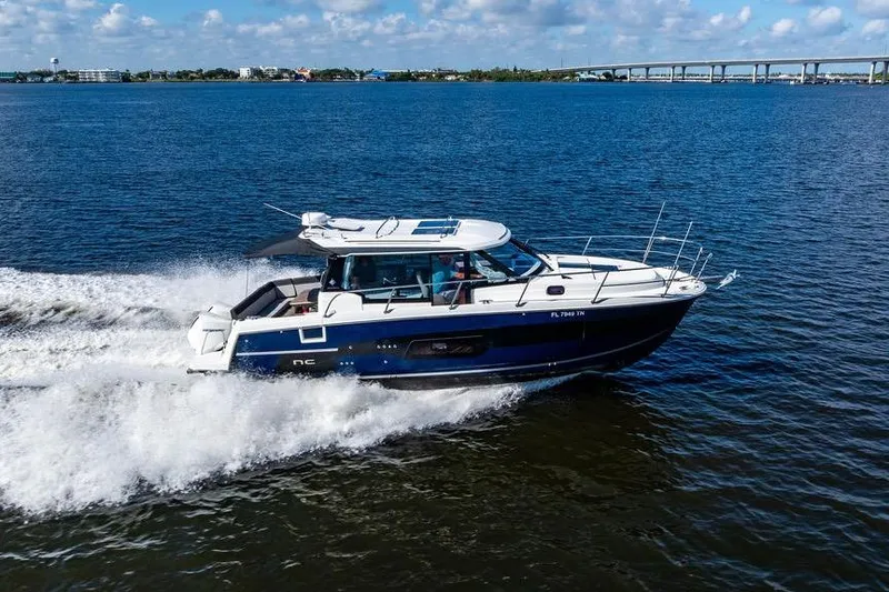 Slide: The Image of 2023 Jeanneau NC 1095 cruising on open water under a clear blue sky. - 15