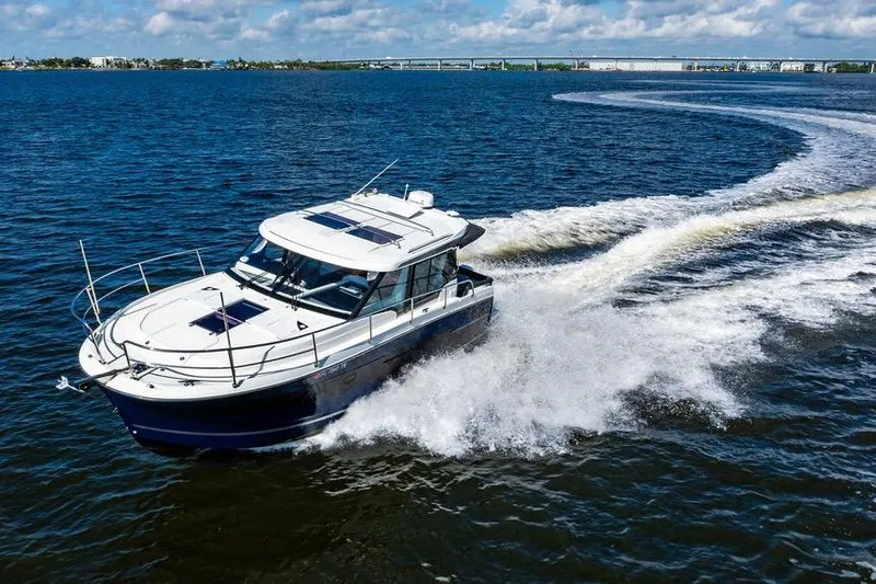 Slide: The Image of 2023 Jeanneau NC 1095 cruising on open water, creating a dynamic wake under a clear sky. - 22