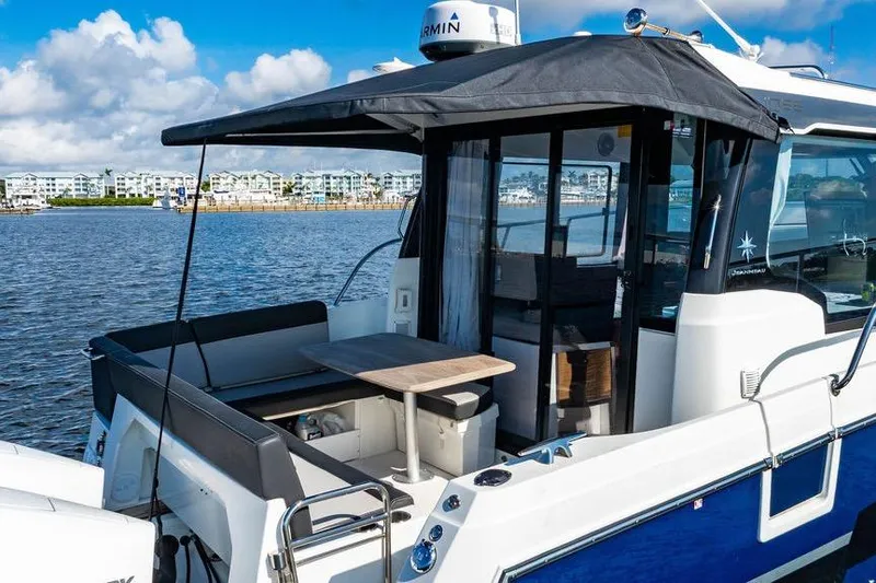 Slide: The Image of 2023 Jeanneau NC 1095 boat with covered seating area, docked by waterfront buildings. - 26