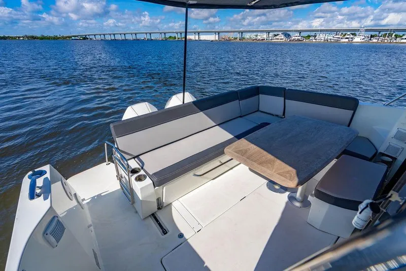 Slide: The Image of 2023 Jeanneau NC 1095 boat deck with seating and table, overlooking serene water and bridge. - 28