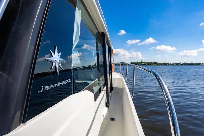 Slide: The Image of 2023 Jeanneau NC 1095 boat cruising on a sunny day, reflecting blue skies and water. - 30