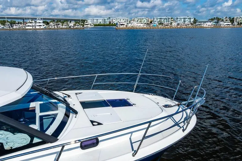Slide: The Image of 2023 Jeanneau NC 1095 boat on calm water with coastal buildings in the background. - 31