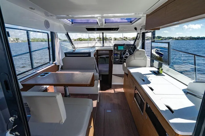 Slide: The Image of Interior of 2023 Jeanneau NC 1095 boat with modern helm, dining area, and scenic water view. - 38
