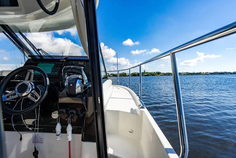 Slide: The Image of 2023 Jeanneau NC 1095 boat cockpit with steering wheel, overlooking serene blue waters. - 47