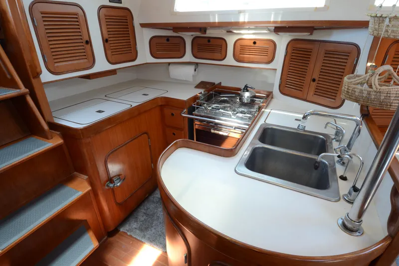 Slide: The Image of 1987 Norseman 400 yacht kitchen with wooden cabinets, dual sinks, and stove. - 23