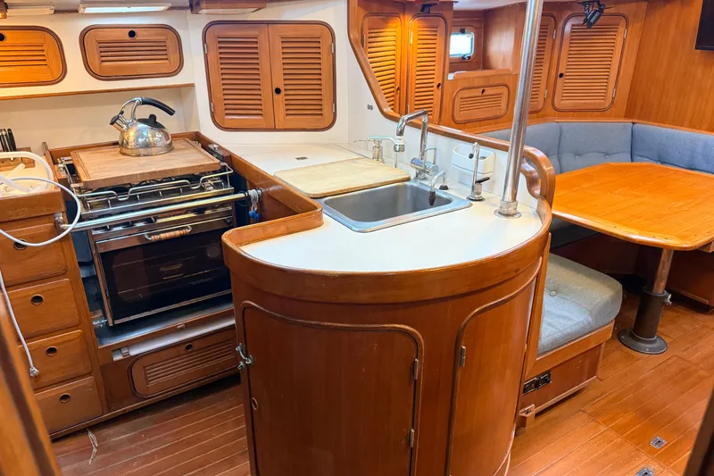 Slide: The Image of 1987 Norseman 400 yacht interior with wooden cabinetry, kitchen, and dining area. - 40