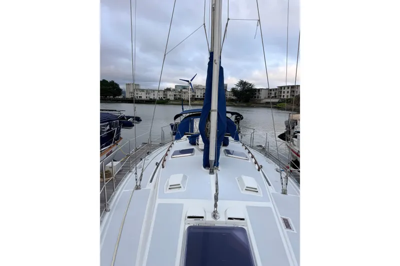 Slide: The Image of 1987 Norseman 400 sailboat docked, showcasing deck and mast, with waterfront buildings in background. - 21