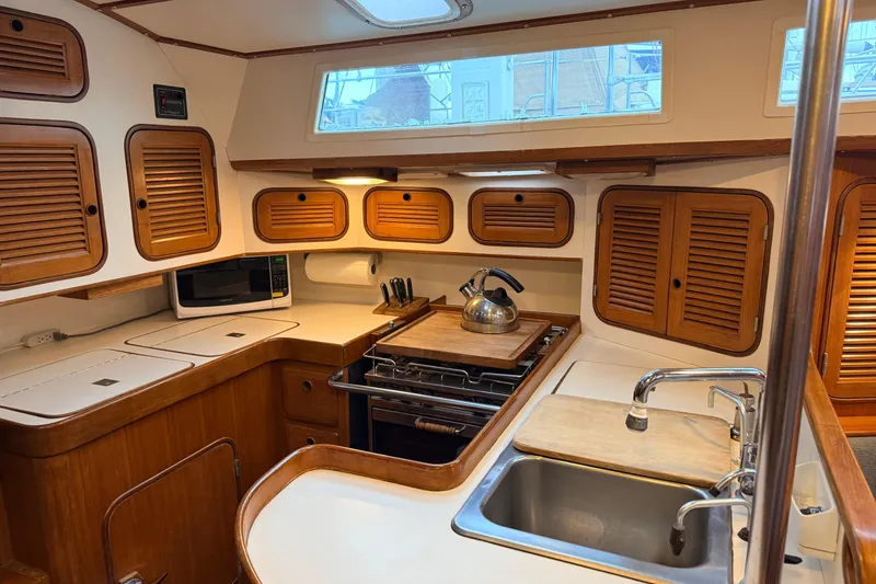 Slide: The Image of Interior of 1987 Norseman 400 sailboat kitchen with wooden cabinets and stainless steel sink. - 35