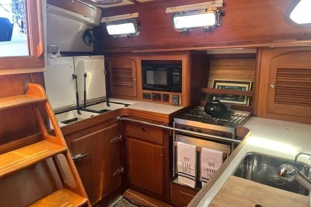 Slide: The Image of 2002 Sabre 452 yacht kitchen with wood cabinetry, stove, microwave, and sink. - 2