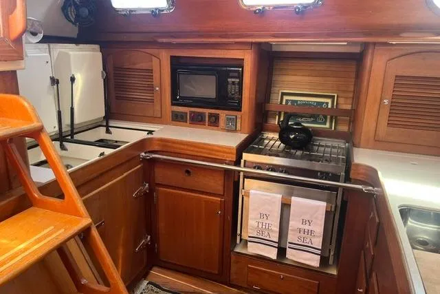 Slide: The Image of 2002 Sabre 452 yacht kitchen with wooden cabinetry, stove, microwave, and nautical decor. - 20