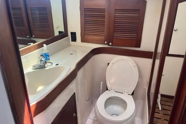 Slide: The Image of 2002 Sabre 452 yacht bathroom with sink, toilet, and wooden cabinetry. - 36