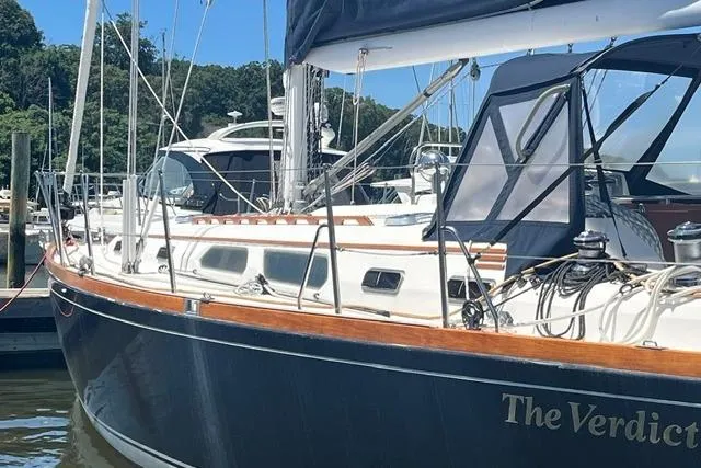 Slide: The Image of Sailboat "The Verdict," Sabre 452, 2002 model, docked in a marina with lush greenery. - 55