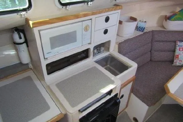 Slide: The Image of Compact kitchen area in a 2000 Albin 28 Tournament Express boat with microwave and sink. - 32