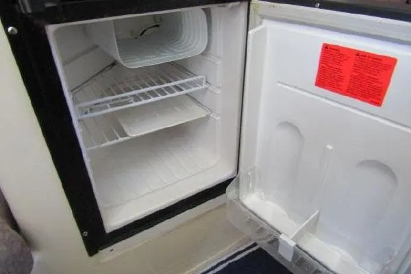 Slide: The Image of Open refrigerator inside a 2000 Albin 28 Tournament Express boat, showing empty shelves. - 36