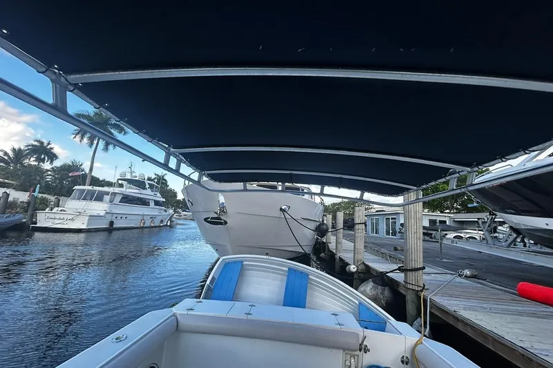 Slide: The Image of 2000 Albin 28 Tournament Express docked, covered by a canopy, with boats and palm trees nearby. - 7