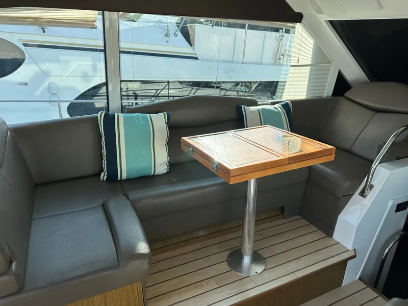 Slide: The Image of Interior of a 2014 Cruisers Yachts 48 Cantius with seating area and wooden table. - 10