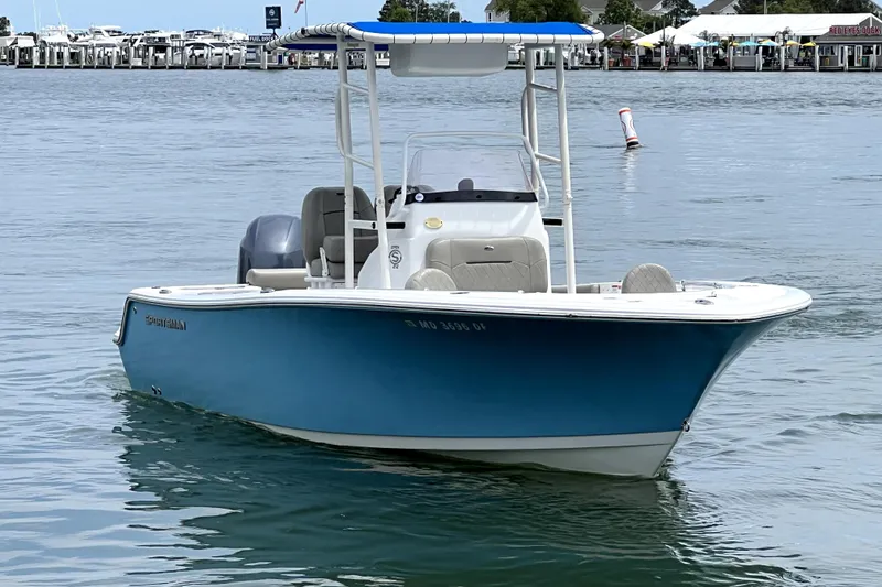Slide: The Image of 2022 Sportsman Open 212 Center Console boat on calm water near a marina. - 13