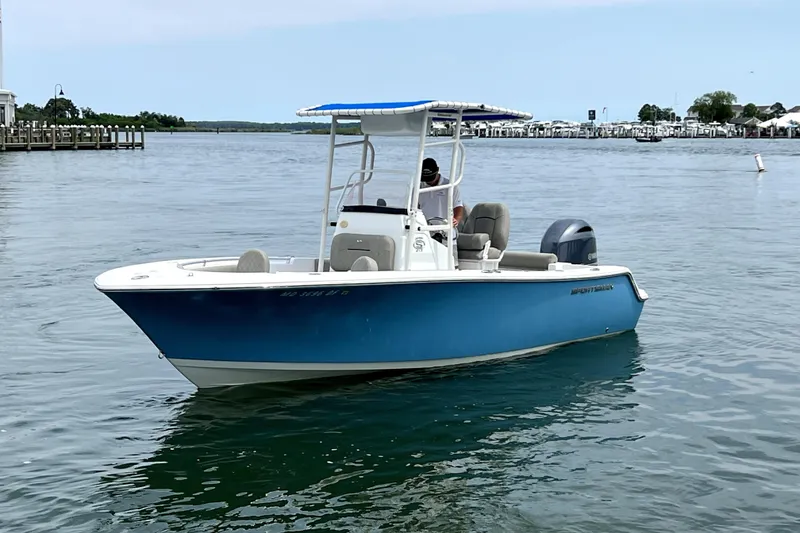 Slide: The Image of 2022 Sportsman Open 212 Center Console boat on calm water, featuring a blue hull and T-top. - 2