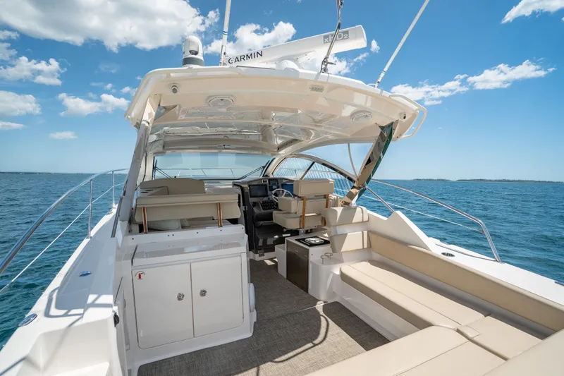 Slide: The Image of 2015 Pursuit SC 365i Sport Coupe yacht interior with seating, ocean view, and clear sky. - 12