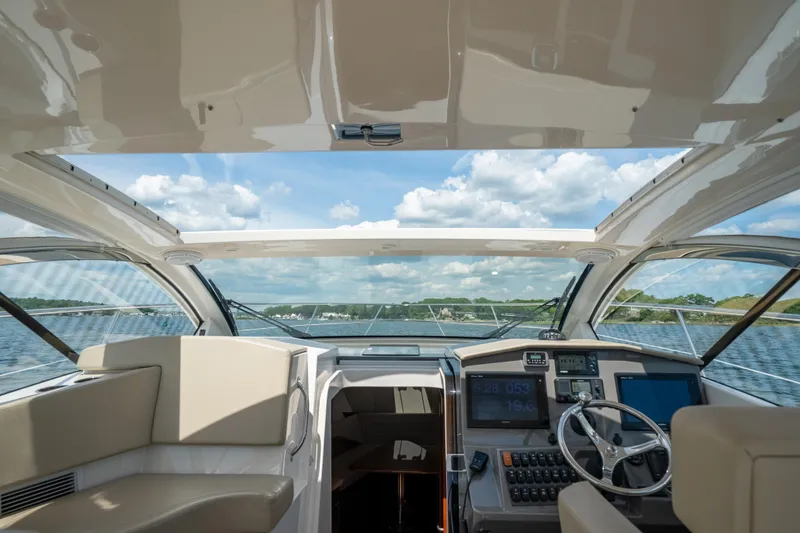 Slide: The Image of Interior view of 2015 Pursuit SC 365i Sport Coupe yacht, featuring helm and seating area. - 19
