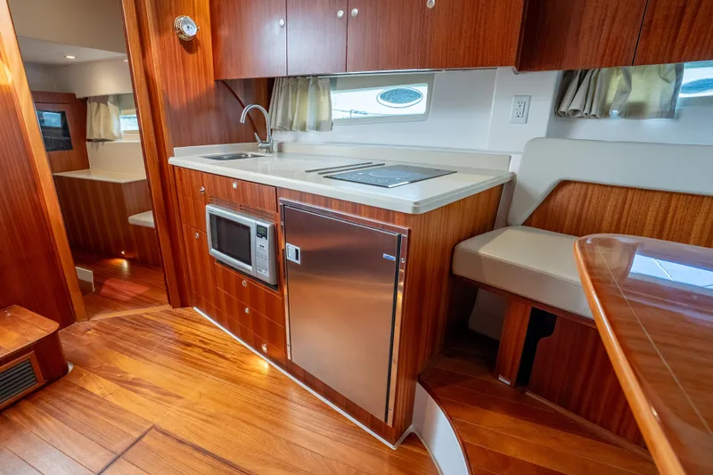 Slide: The Image of 2015 Pursuit SC 365i Sport Coupe interior with wood finish, kitchenette, and seating area. - 25