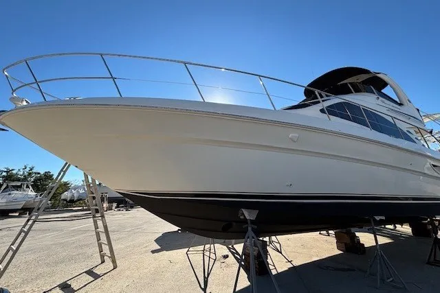 Slide: The Image of 2004 Sea Ray 420 Sedan Bridge yacht on stands, viewed from below, under clear blue sky. - 106