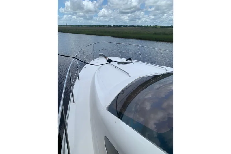Slide: The Image of 2004 Sea Ray 420 Sedan Bridge yacht on calm water under a cloudy sky. - 1