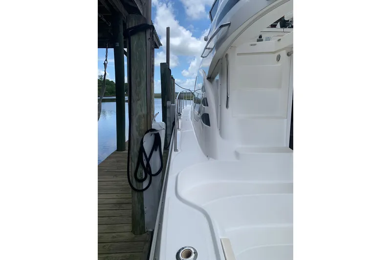 Slide: The Image of 2004 Sea Ray 420 Sedan Bridge yacht docked, showcasing sleek white exterior and serene waterside view. - 13