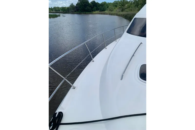Slide: The Image of 2004 Sea Ray 420 Sedan Bridge yacht on calm river, showcasing sleek deck design. - 16