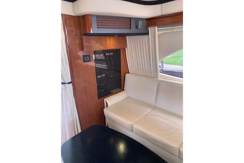 Slide: The Image of Interior of 2004 Sea Ray 420 Sedan Bridge with cream sofa and wood paneling. - 30