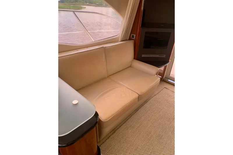 Slide: The Image of Luxurious interior of 2004 Sea Ray 420 Sedan Bridge with beige sofa and window view. - 32