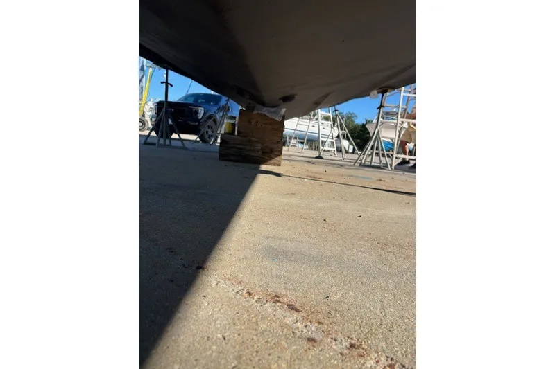 Slide: The Image of Underneath view of a 2004 Sea Ray 420 Sedan Bridge on blocks, with vehicles and ladders nearby. - 93