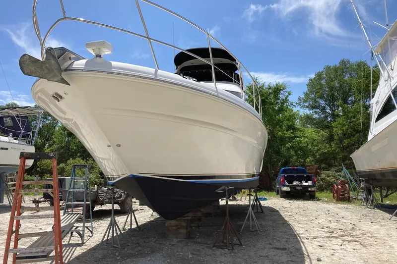 Slide: The Image of 2004 Sea Ray 420 Sedan Bridge yacht on dry dock, surrounded by trees and equipment. - 60
