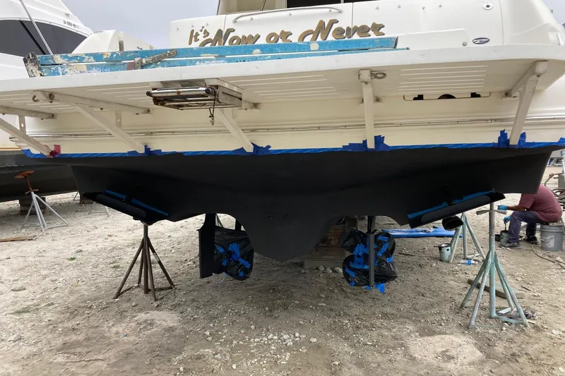 Slide: The Image of 2004 Sea Ray 420 Sedan Bridge on stands, undergoing maintenance on a sandy surface. - 62