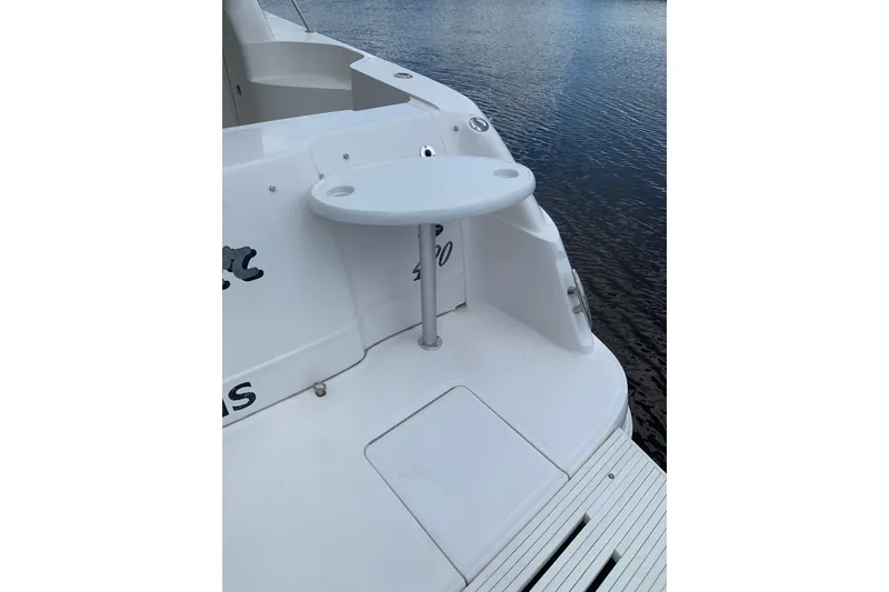 Slide: The Image of 2004 Sea Ray 420 Sedan Bridge boat stern with small table, docked on calm water. - 8