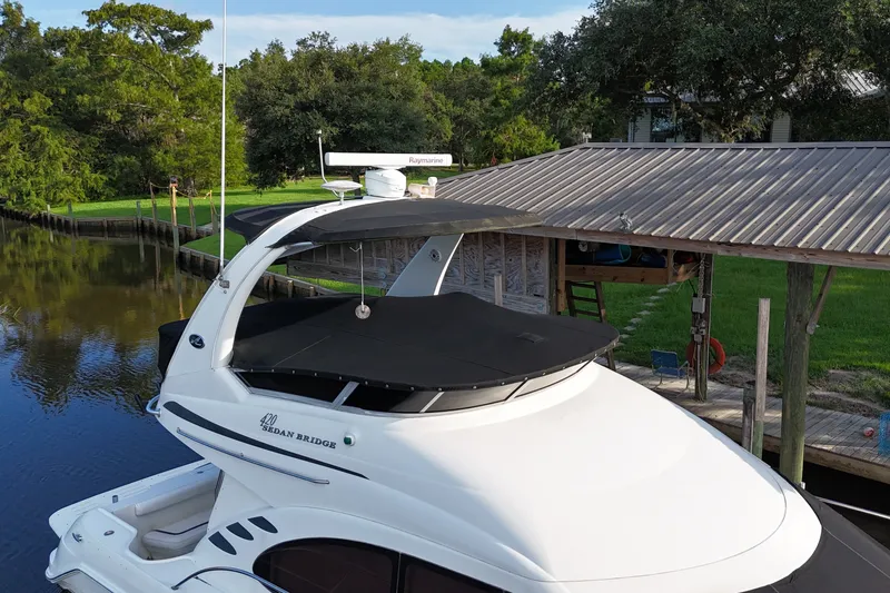Slide: The Image of 2004 Sea Ray 420 Sedan Bridge yacht docked by a serene riverside. - 2