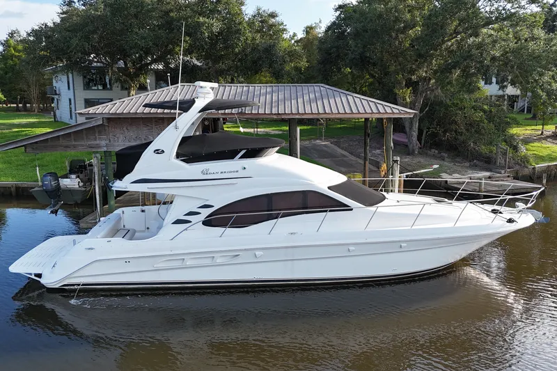 Slide: The Image of 2004 Sea Ray 420 Sedan Bridge yacht docked by a riverside house. - 1