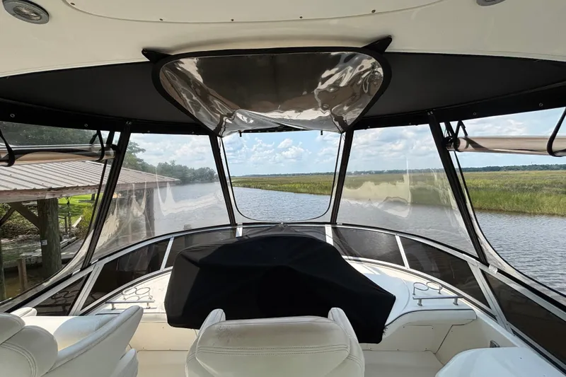 Slide: The Image of 2004 Sea Ray 420 Sedan Bridge interior view with scenic waterway backdrop. - 64