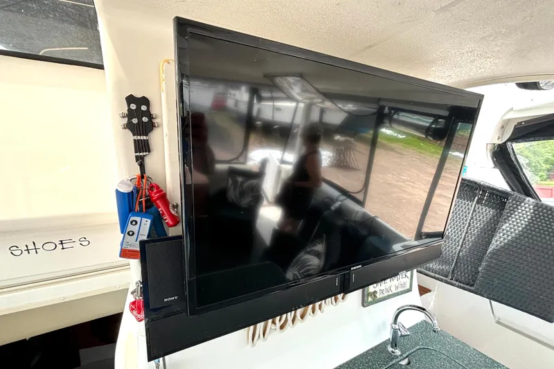 Slide: The Image of 1999 Silverton 453 Motor Yacht interior with mounted TV, ukulele, and sink area. - 13