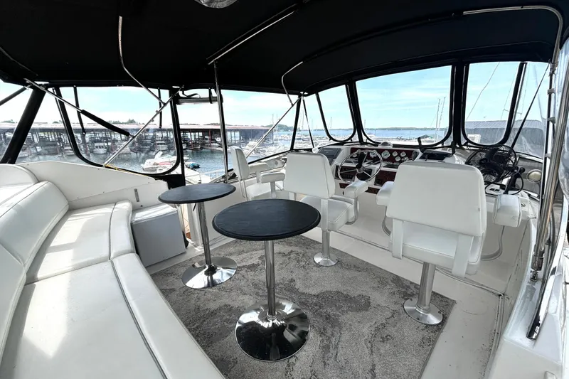 Slide: The Image of 1999 Silverton 453 Motor Yacht interior with white seating, helm, and marina view. - 14