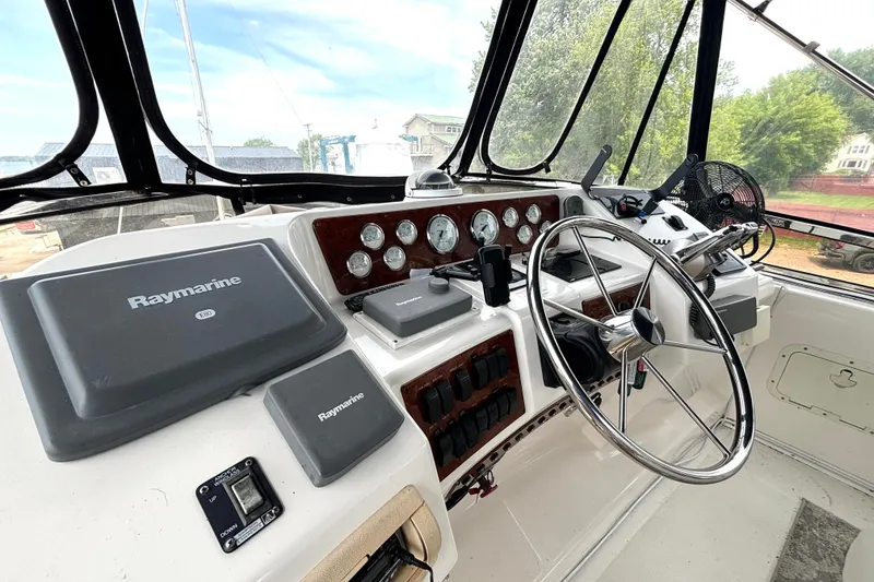 Slide: The Image of 1999 Silverton 453 Motor Yacht helm with Raymarine navigation system and steering wheel. - 17